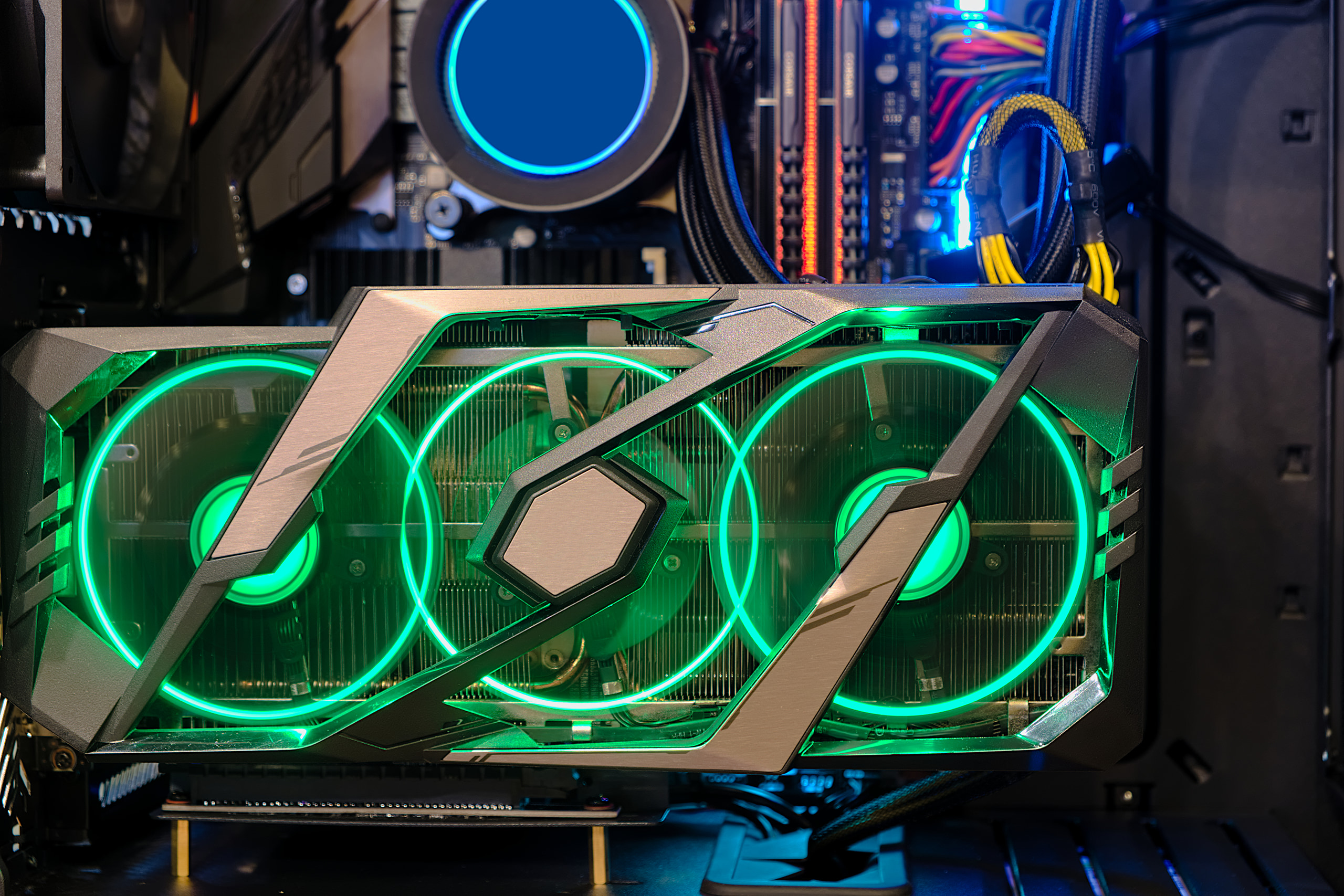 Triple-fan graphics card illuminated with green ring LEDs under thermal load